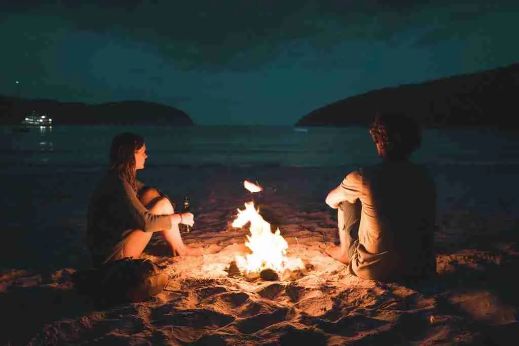 Starting over at 40 with nothing. Two people sat by a fire looking at the sea