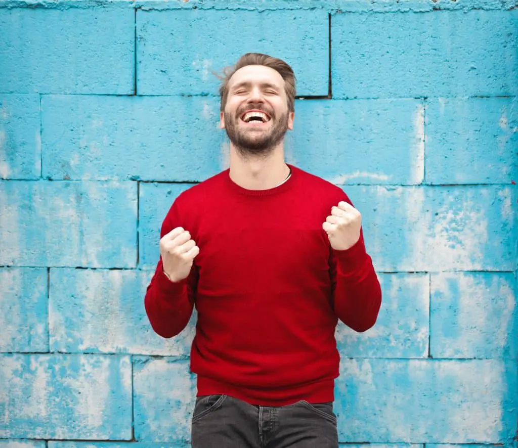 What is important in life money or happiness?
Man celebrating against a blue wall background