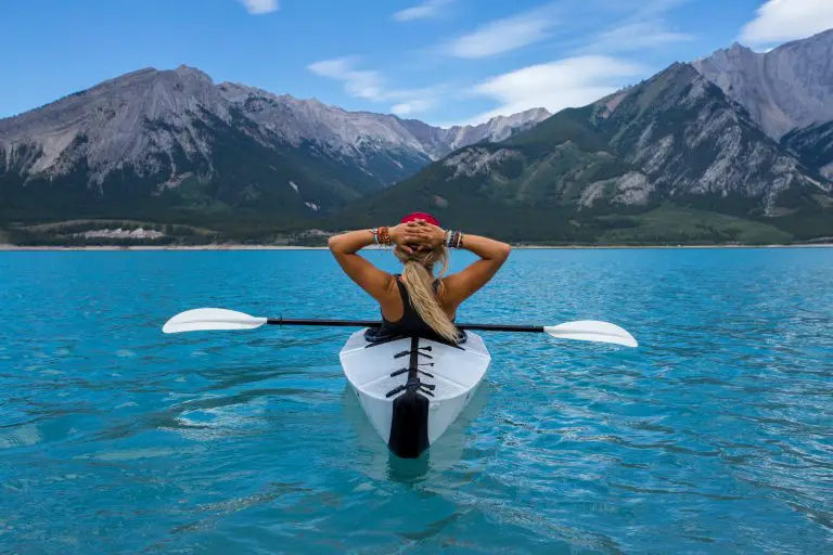 lady in a canoe holding hands behind head on a lake